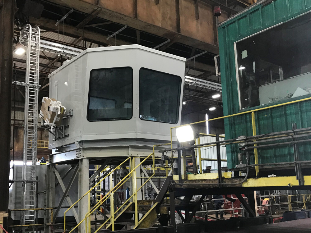 Industrial manufacturing control room with protected operator station and plant equipment.